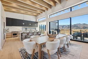 Dining room with a mountain view, beam ceiling, light wood finished floors, and a towering ceiling