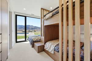 Bedroom with expansive windows, a mountain view, access to outside, light colored carpet, and recessed lighting