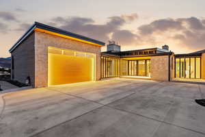 Property exterior at dusk featuring stone siding, a chimney, and driveway