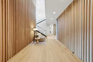 Hall with wood finished floors, recessed lighting, wood walls, and stairs