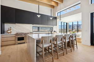Kitchen with healthy amount of natural light, modern cabinets, light stone counters, a mountain view, and beam ceiling