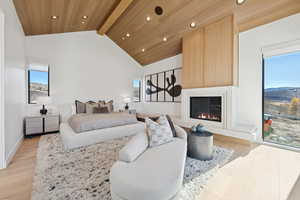 Bedroom featuring multiple windows, light wood finished floors, a fireplace, high vaulted ceiling, and recessed lighting