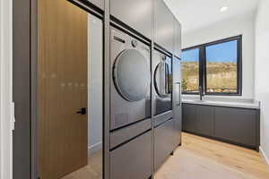 Laundry area with light wood finished floors and washing machine and clothes dryer