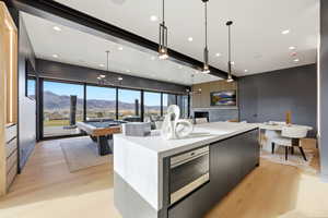 Kitchen with a mountain view, modern cabinets, billiards table, dark cabinetry, and light wood-type flooring