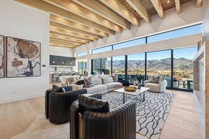 Living room featuring a mountain view, light wood-type flooring, a high ceiling, and a wood ceiling with exposed beams