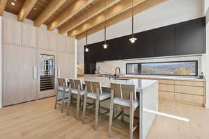 Kitchen with light brown cabinets, modern cabinets, a breakfast bar area, dark cabinets, and hanging light fixtures