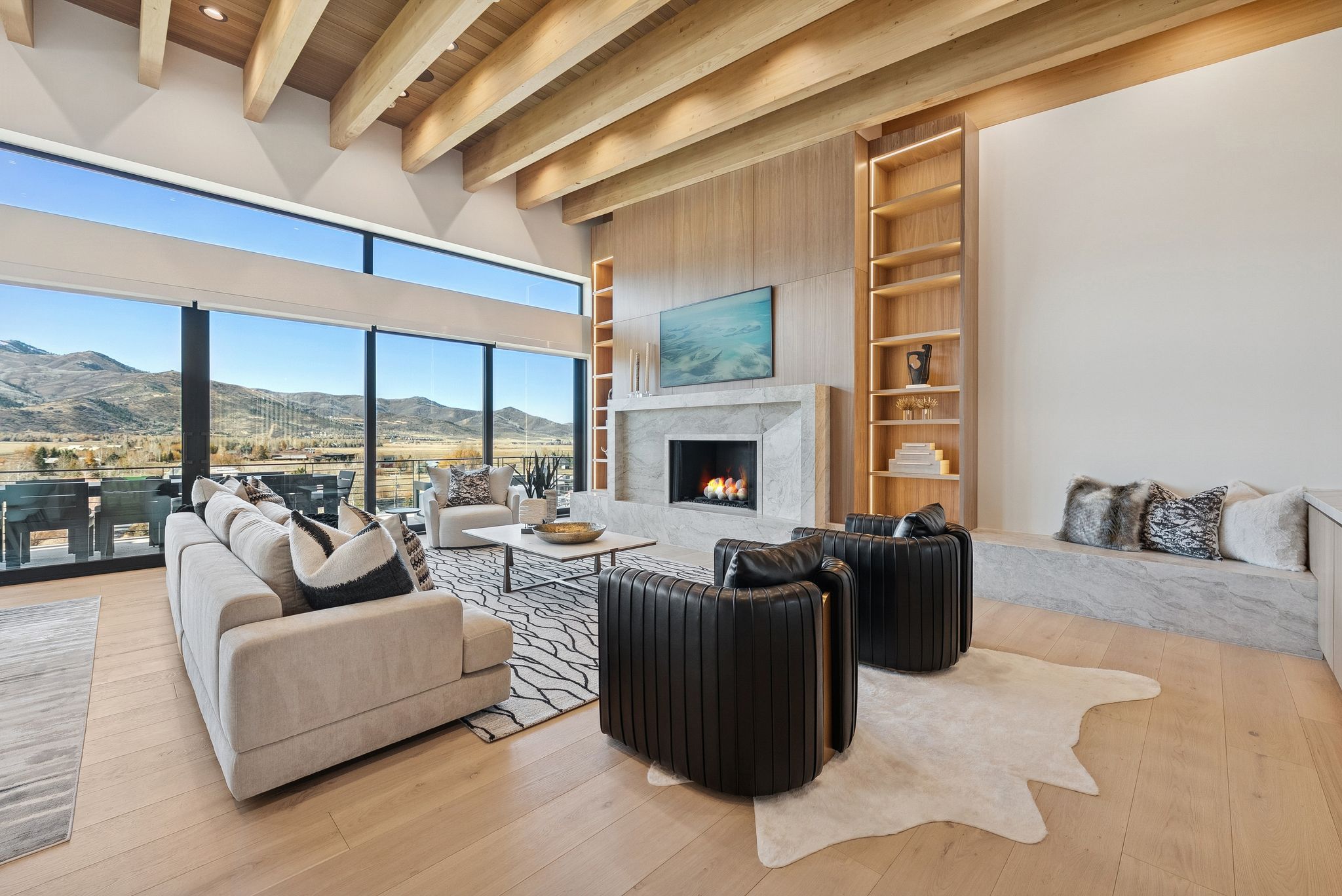 Living room featuring built in shelves, a mountain view, a high end fireplace, hardwood / wood-style flooring, and a wooden ceiling with exposed beams