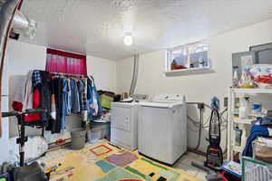 Laundry area featuring a textured ceiling and independent washer and dryer