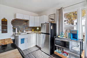 Kitchen featuring stainless steel appliances, light countertops, white cabinets, tasteful backsplash, and light wood-type flooring