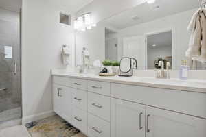 Bathroom featuring double vanity, a stall shower, and light tile patterned floors