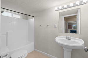 Full bathroom featuring a textured wall, a textured ceiling, shower / tub combination, and light tile patterned flooring