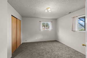 Unfurnished bedroom with a closet, carpet, and a textured ceiling