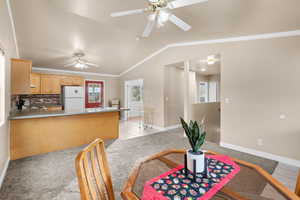 Dining space with vaulted ceiling, ornamental molding, light tile patterned flooring, and light colored carpet