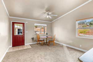 Dining area with crown molding, light colored carpet, a ceiling fan, and light tile patterned flooring