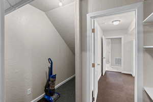 Hallway with a textured wall and dark colored carpet