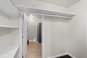 Walk in closet with light wood-style flooring