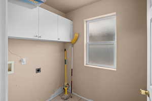 Laundry area with cabinet space, tile patterned flooring, hookup for a washing machine, and electric dryer hookup