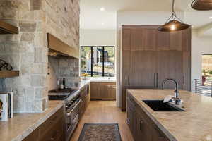 Kitchen featuring light countertops, stainless steel appliances, light wood-style flooring, pendant lighting, and backsplash