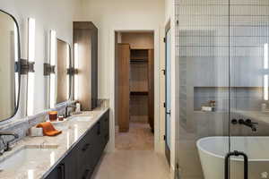 Bathroom with a walk in closet, a soaking tub, double vanity, light tile patterned flooring, and a stall shower