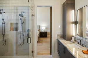 Bathroom featuring ensuite bathroom, vanity, a shower stall, tasteful backsplash, and light wood-type flooring