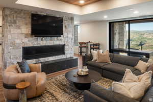 Living area featuring wood finished floors, a stone fireplace, recessed lighting, and wooden ceiling