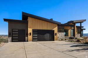 Contemporary home featuring stone siding, driveway, a garage, and a mountain view