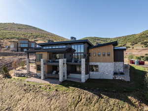 Back of house with a patio, stone siding, a mountain view, and a metal roof