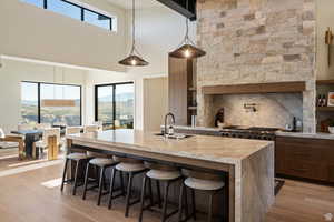 Kitchen featuring a breakfast bar, healthy amount of natural light, light wood-style floors, hanging light fixtures, and a high ceiling