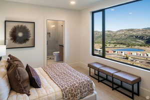 Bedroom with connected bathroom, light carpet, a water and mountain view, and recessed lighting