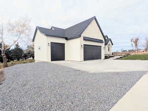 View of side of home featuring concrete driveway, a standing seam roof, a shingled roof, a metal roof, and an attached garage