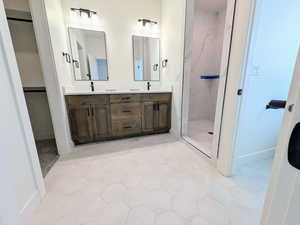 Full bathroom featuring double vanity, a marble finish shower, and a spacious closet
