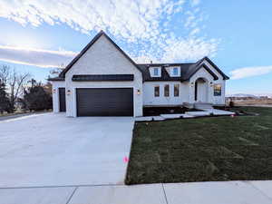 Modern farmhouse featuring driveway, a front lawn, a garage, and a standing seam roof