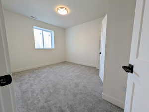 Spare room featuring light carpet and baseboards