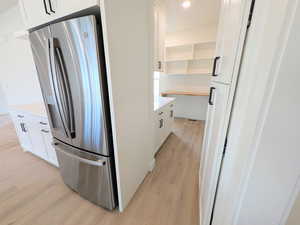 Kitchen featuring stainless steel fridge with ice dispenser, light wood-type flooring, white cabinetry, and recessed lighting