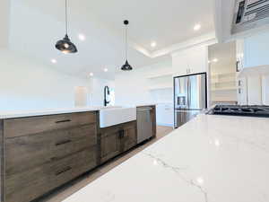 Kitchen with white cabinets, pendant lighting, stainless steel appliances, exhaust hood, and open shelves