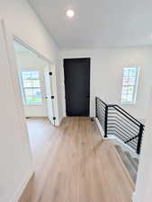 Hall featuring light wood-style floors, healthy amount of natural light, and recessed lighting