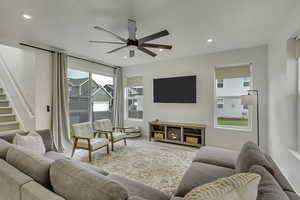 Living room featuring recessed lighting, a ceiling fan, and stairway