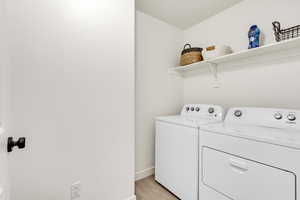 Washroom featuring washer and dryer and light wood-style flooring