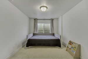 Carpeted bedroom featuring baseboards and a textured ceiling