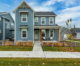 View of front facade with board and batten siding, a porch, a front yard, and roof with shingles