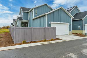 View of front of house featuring board and batten siding, driveway, and a garage