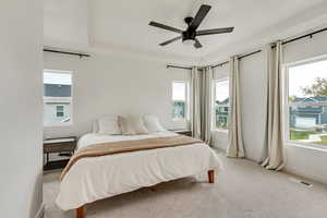 Bedroom with light colored carpet, multiple windows, and ceiling fan