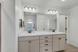 Full bathroom with double vanity and light wood-style floors