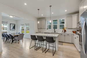 Kitchen with pendant lighting, a kitchen island, recessed lighting, a breakfast bar, and wood finish floors
