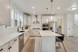 Kitchen with a breakfast bar area, decorative light fixtures, light wood finished floors, a center island, and stainless steel appliances
