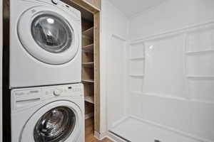 Washroom with estacked washer and dryer and wood finished floors
