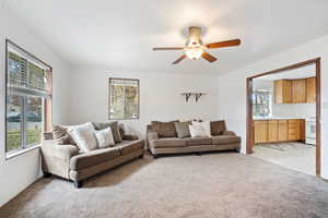 Living area featuring light colored carpet and ceiling fan