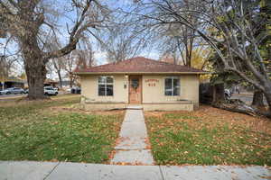 Bungalow-style house with a front yard, concrete block siding, and roof with shingles