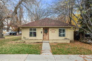 Bungalow featuring concrete block siding, a front yard, and roof with shingles