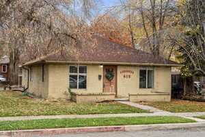 Bungalow with concrete block siding, a front yard, and roof with shingles